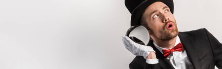 panoramic shot of emotional magician listening to magic ball, isolated on greyの写真素材