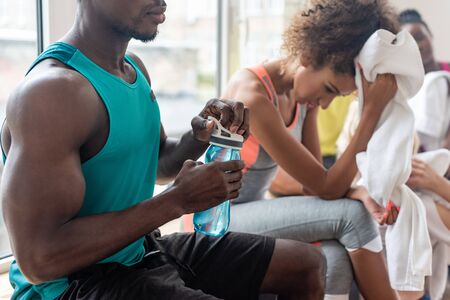 Selective focus of african american dancer holding sports bottle while resting in dance studioの写真素材