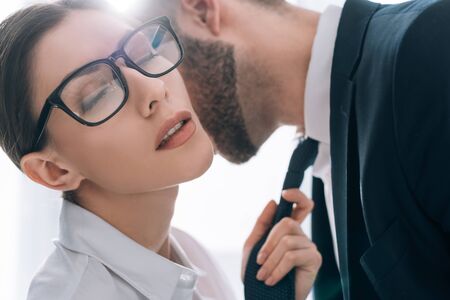 businessman kissing attractive secretary with closed eyes in officeの写真素材
