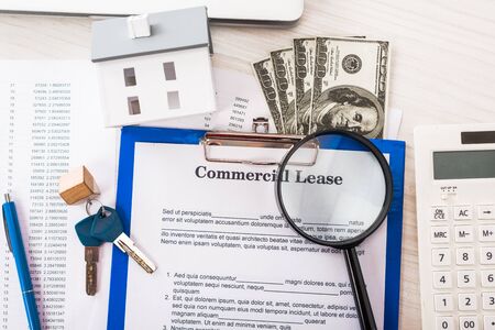 top view of document with commercial lease lettering on clipboard near keys, money, house model,...