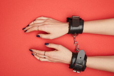 cropped view of woman in black handcuffs isolated on red