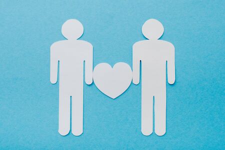 top view of paper cut figures of homosexual couple isolated on blue, human rights conceptの写真素材