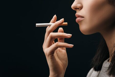Side view of woman holding cigarette isolated on blackの写真素材