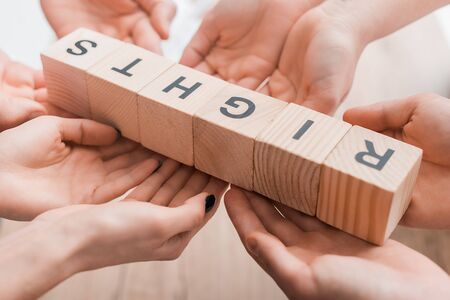 cropped view of four people holding wooden cubes with rights lettering
