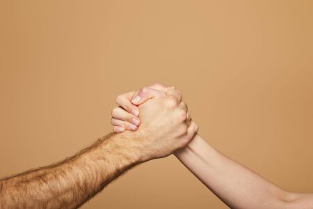 cropped view of man and woman arm wrestling isolated on beige
