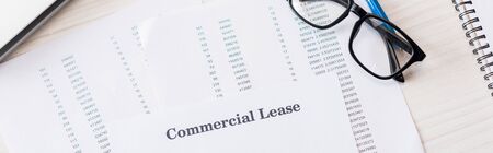 panoramic shot of document with commercial lease lettering near glasses on desk
