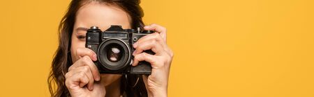 panoramic shot of young woman taking phone on digital camera isolated on yellow