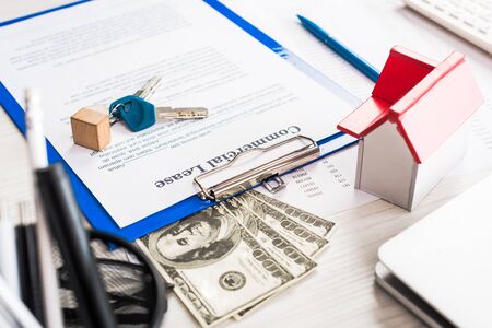 selective focus of document with commercial lease lettering on clipboard near keys, house model and...