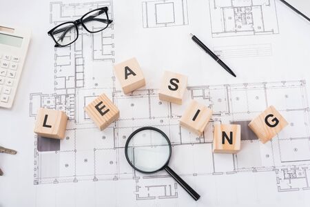 top view of wooden cubes with leasing lettering near glasses, pen, magnifier and calculator on...