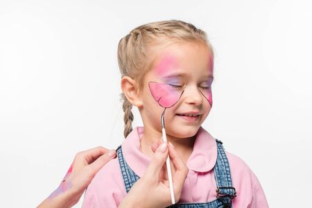 cropped view of artist painting butterfly on face of adorable child isolated on white
