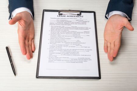 cropped view of businessman near clipboard with lease agreement lettering and pen