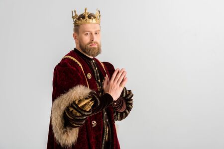 king with crown showing praying hands isolated on greyの写真素材