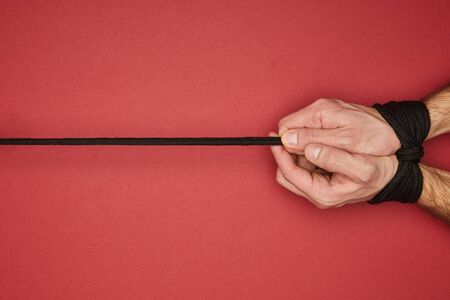 cropped view of man with rope on hands isolated on redの写真素材