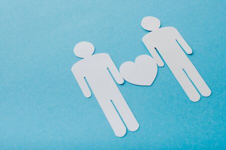 paper cut figures of homosexual couple isolated on blue, sexual equality conceptの写真素材
