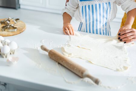 cropped view of mother and daughter cooking and holding dough