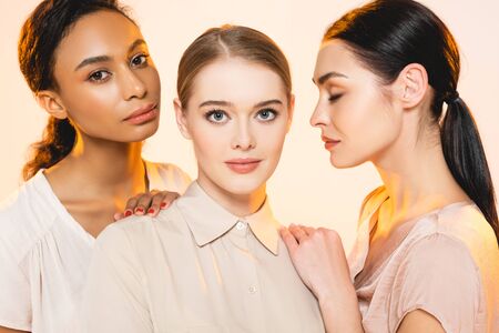 three beautiful multicultural women with makeup isolated on beigeの写真素材