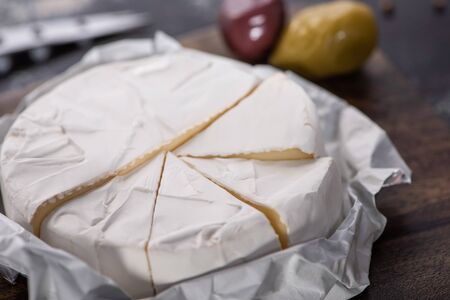 close up view of cut brie cheese on wooden cutting board