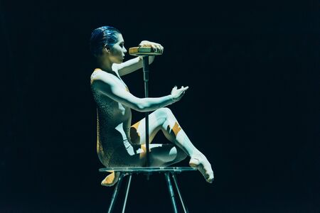 KYIV, UKRAINE - NOVEMBER 1, 2019: Beautiful gymnast performing with equipment in circus isolated on blackのeditorial素材