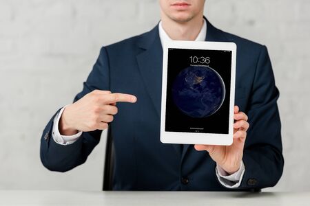 cropped view of realtor in suit pointing with finger at ipad on whiteのeditorial素材