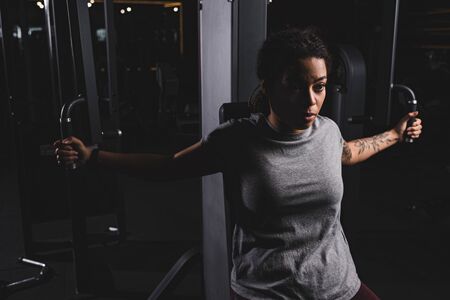 young african american girl with tattoo training on gym machine
