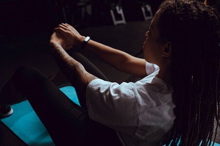 selective focus of tattooed african american woman with dreadlocks doing exercise in gymの写真素材