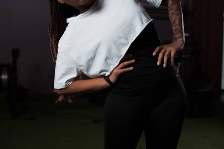 cropped view of tattooed african american woman with hands on hips exercising in gym