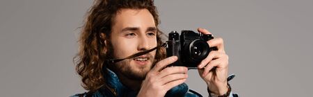 panoramic shot of smiling man taking photo isolated on grey