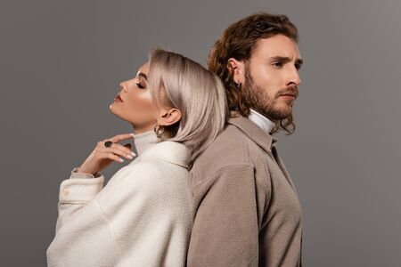 back to back view of woman in white coat with closed eyes and man in shirt isolated on grey