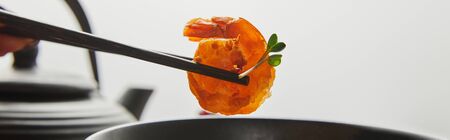 cropped view of woman holding shrimp with chopsticks near bowl isolated on grey, panoramic shotの写真素材