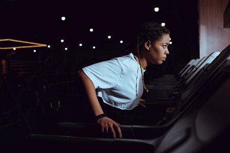 Side view of african american woman running on treadmill in gym