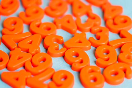 Selective focus of orange plastic numbers on blue backgroundの写真素材