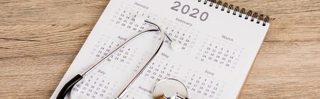 Panoramic shot of stethoscope on calendar of 2020 year on wooden backgroundの写真素材