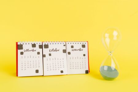 Calendar with autumn months and hourglass on yellow background