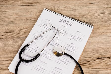 High angle view of calendar of 2020 year with stethoscope on wooden surfaceの写真素材