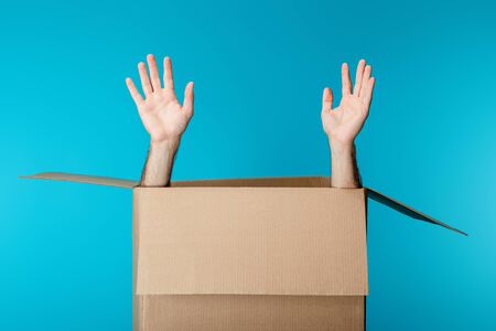Hands of courier in cardboard package isolated on blue