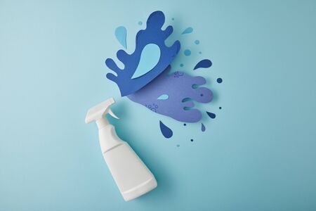 top view composition with spray bottle and blue water splashes made of paper, on blue