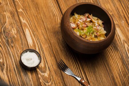 delicious varenyky with cracklings in bowl served with sour cream on wooden tableの写真素材