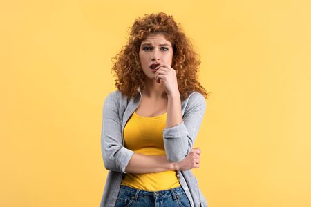 Worried redhead young woman, isolated on yellowの写真素材