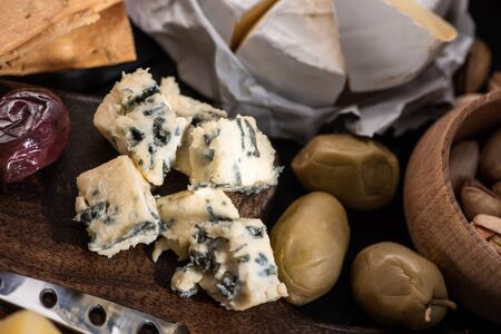 Selective focus of dorblu with dried olives, bowl of pistachios, camembert and crackers on trayの写真素材