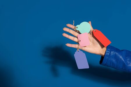 cropped view of african american woman with empty labels on hand on blue background