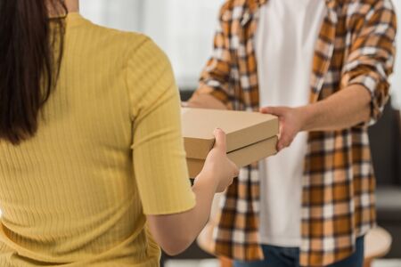 Cropped view of courier giving pizza in boxes to manの写真素材
