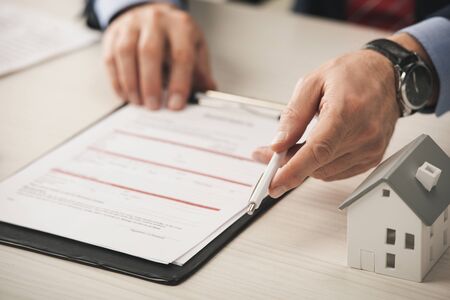 cropped view of agent holding pen near clipboard and carton house model