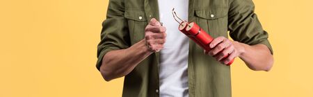 panoramic shot of man holding dynamite sticks and lighter, isolated on yellow