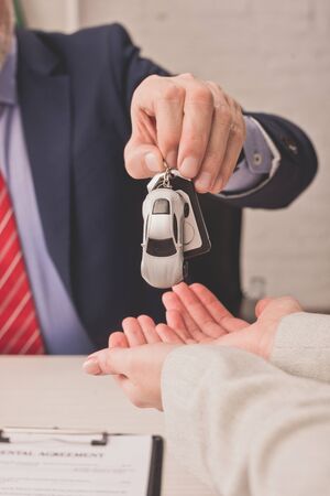 cropped view of agent giving car key to client with cupped handsの写真素材