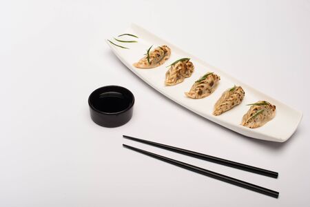 delicious gyoza on plate near chopsticks and soy sauce on white backgroundの写真素材