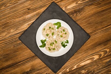 top view of delicious Khinkali with cilantro on plate on brown wooden tableの写真素材