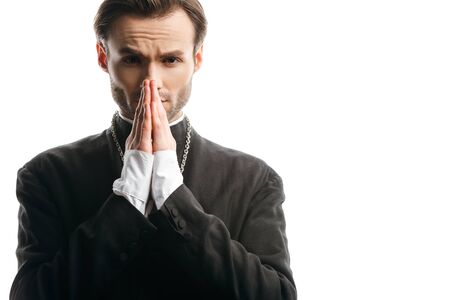 serious, concentrated catholic priest praying while looking at camera isolated on whiteの写真素材