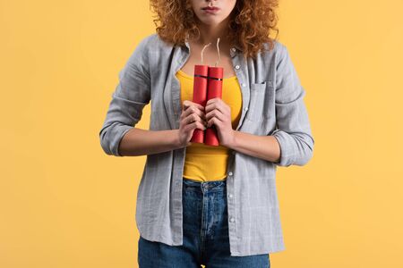 cropped view of angry woman holding dynamite, isolated on yellow