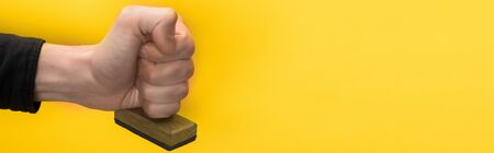 panoramic shot of man holding stamp isolated on yellow, quality conceptの写真素材
