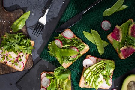 top view of vegetarian sandwiches with fresh vegetables on cloth and cutting boards with fork and...